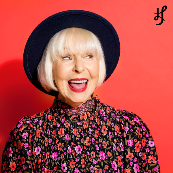 Beauty photography campaign of happy mature model wearing floral shirt featuring Lip Rouge Lipstick in Bob's Your Uncle - a bright, vibrant warm red lipstick